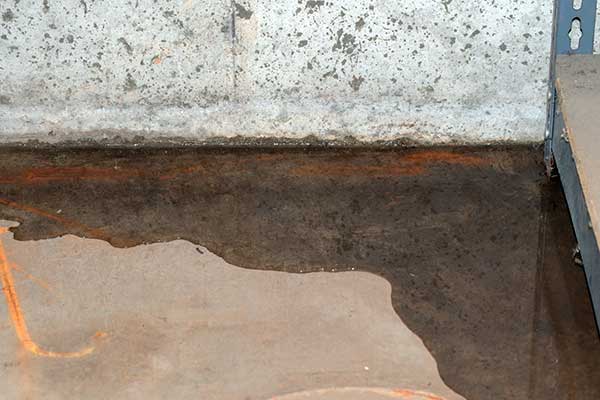 Block basement wall with puddled water and rust stained floor